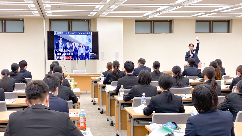 社員が前方のモニターを使った説明を受けている研修風景